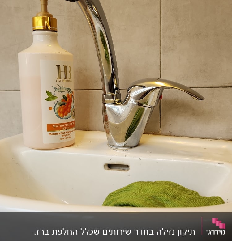 ברז כרום בכיור עם סבון נוזלי ומטלית ירוקה